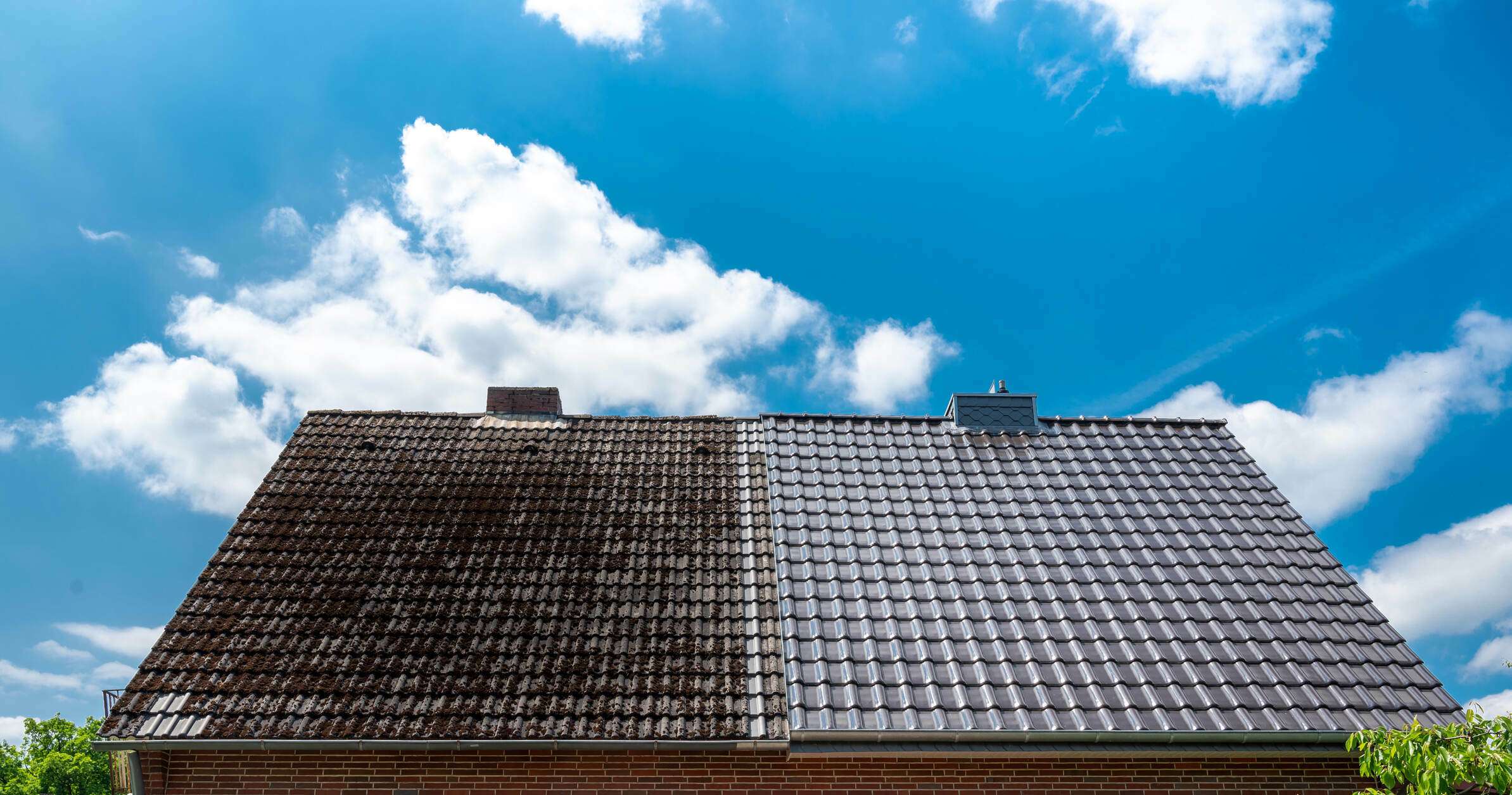 A half-cleaned house roof showing the before and after effect of a roof maintenance cleaning.